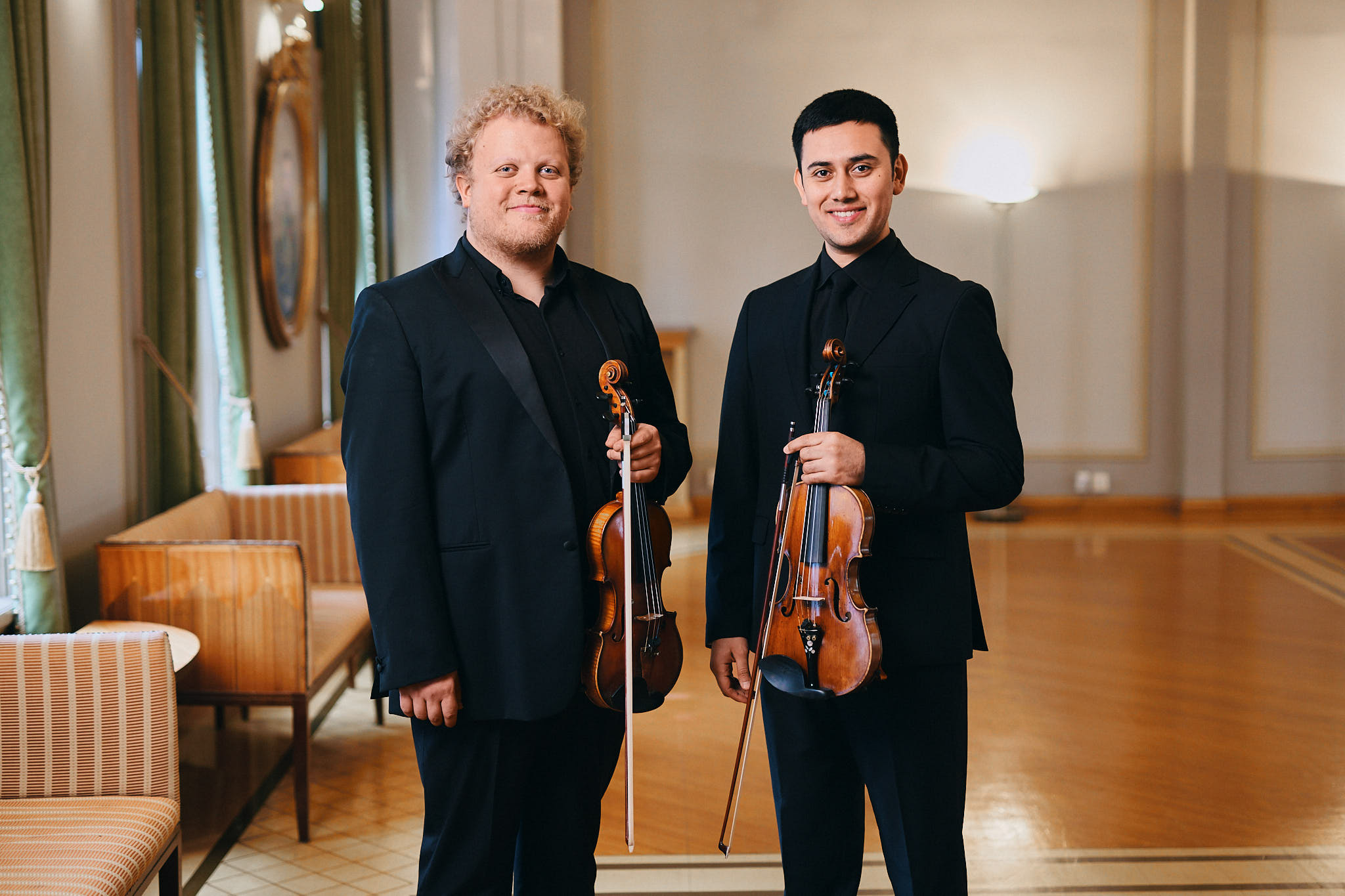 Kaksi miestä seisovat rinnakkain viulut kädessä. 